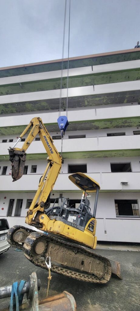 クレーンで油圧ショベルを吊り上げる重機搬入作業
